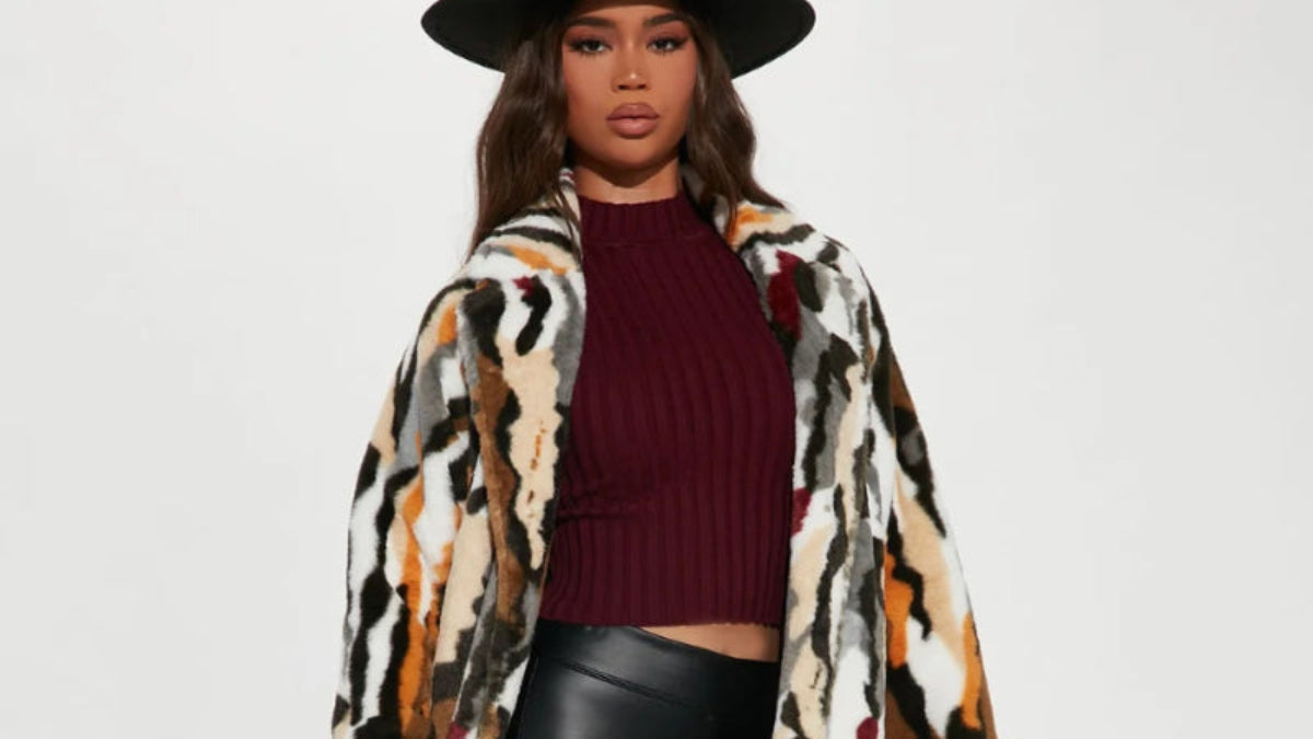 Woman wearing a patterned coat, black leggings, and black boots on a white background